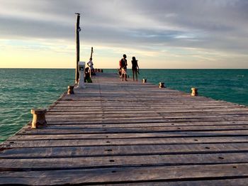 Pier on sea against cloudy sky