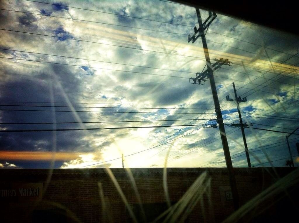 sky, cloud - sky, cloudy, glass - material, low angle view, cloud, transparent, silhouette, sunset, indoors, reflection, window, weather, power line, built structure, dusk, cable, architecture, glass, nature