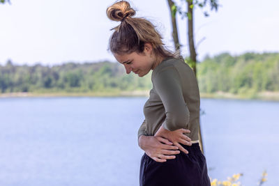 Young caucasian woman touching her side, feeling pain on her back and hip while exercising