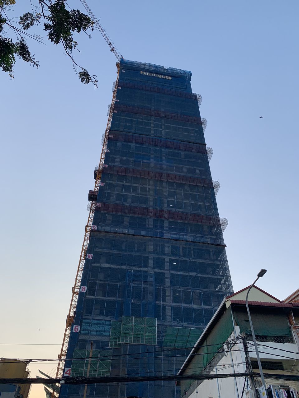 LOW ANGLE VIEW OF CRANE AGAINST BUILDING AGAINST CLEAR SKY