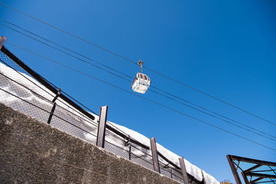 Low angle view of ski lift against clear blue sky