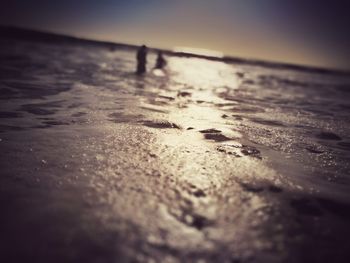 Close-up of wet sand on beach against sky