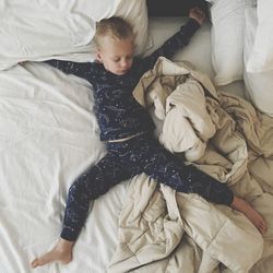 Full length of boy sleeping on bed at home