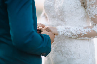 Midsection of newlywed couple holding hands