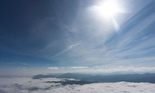 Scenic view of snow covered mountains against bright sun