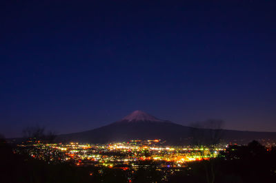 Illuminated city against sky at night