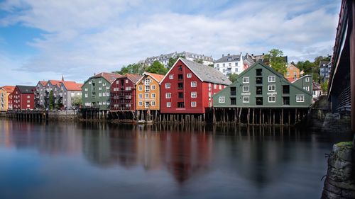 Buildings by river against sky