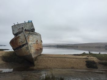 Close-up of abandoned boat on beach against sky