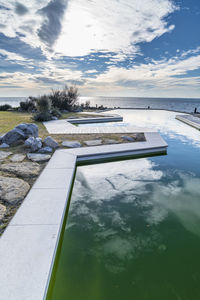 Scenic view of swimming pool by lake against sky