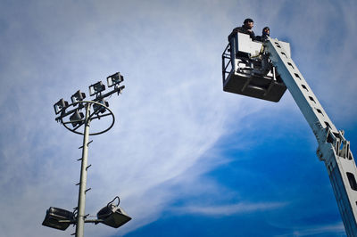 Low angle view of construction workers on cherry picker