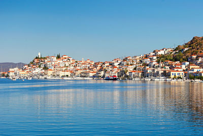 Townscape by sea against clear blue sky