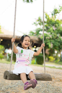 Happy girl playing on swing at playground