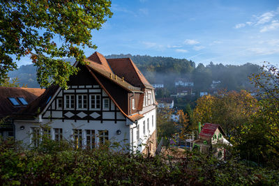 Houses by trees on field against sky