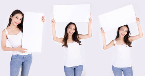 Portrait of smiling young woman standing against white background