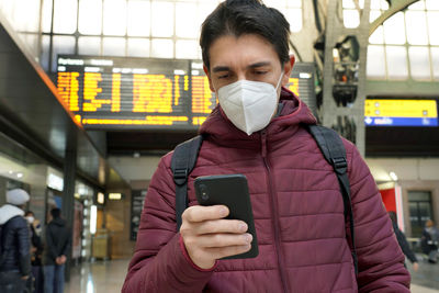 Man wearing mask using phone at airport