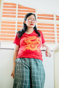 Portrait of a beautiful young woman standing against wall