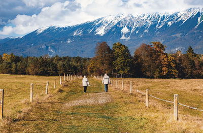 Senior couple hiking on a path on a plain under mountain.