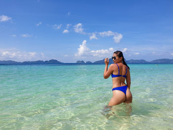 Young woman in bikini on beach against sky