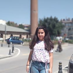 Portrait of girl smiling while standing on road in city