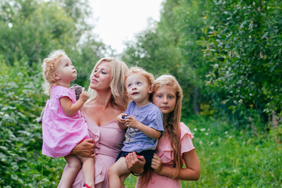 Portrait of a mom with two daughters and son standing against plants