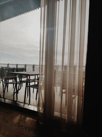 Chairs and table against sky seen through glass window