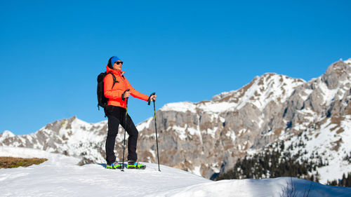 Man standing on rock against blue sky