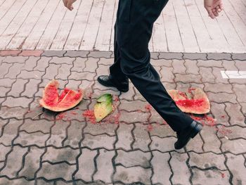 Low section of man walking over crushed watermelon