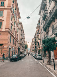 View of city street and buildings against sky and mountain