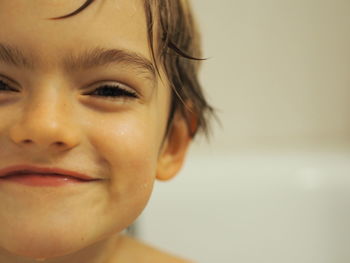 Close-up portrait of smiling wet boy at home