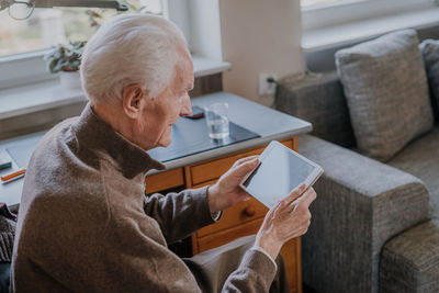 Smiling senior man using digital tablet at home