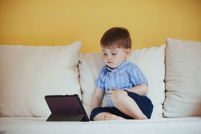 Boy looking at camera while sitting on sofa at home