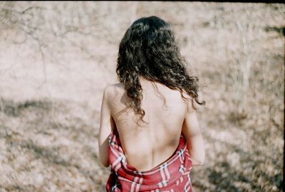 Rear view of topless woman on field