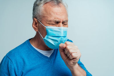 Portrait of man wearing mask against blue background