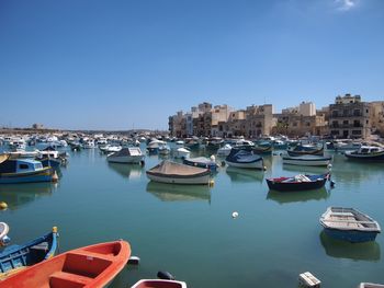 Boats moored at harbor against clear blue sky