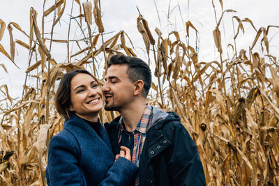 Moments of tenderness of happy couple in love on walk outside the city in autumn among cornfield