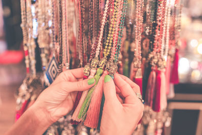 Cropped hands of woman holding jewelry hanging at market