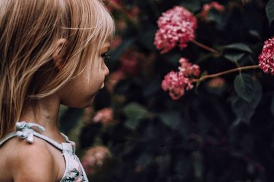 Close-up of girl looking at flowers blooming outdoors