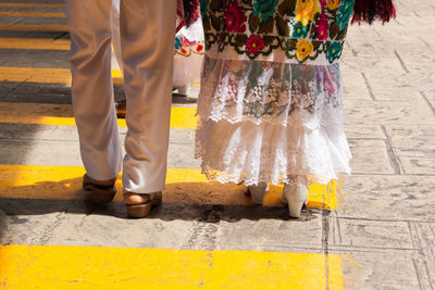 Low section of man and woman standing on footpath during sunny day