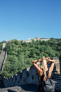 Rear view of woman tying hair while standing at great wall of china