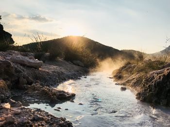 Scenic view of waterfall against sky during sunset