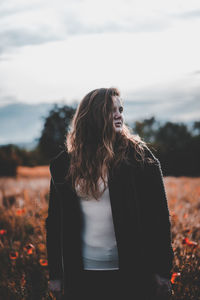 Woman standing on field against sky during autumn