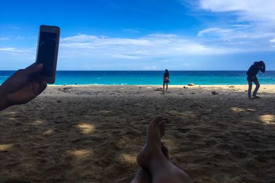 Low section of woman on beach against sky