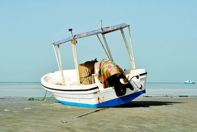 Boat moored on beach against clear sky