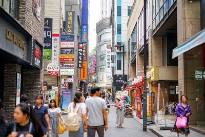 People walking on street amidst buildings in city