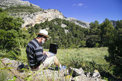 Rear view of man using mobile phone against sky