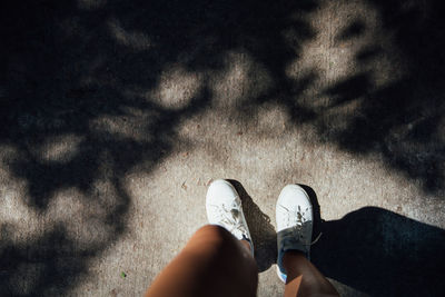 Low section of young woman standing on road