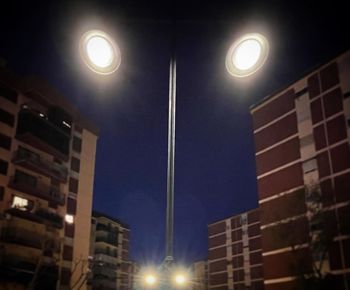 Low angle view of illuminated street lights against buildings at night