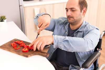 Midsection of man cutting tomato on table