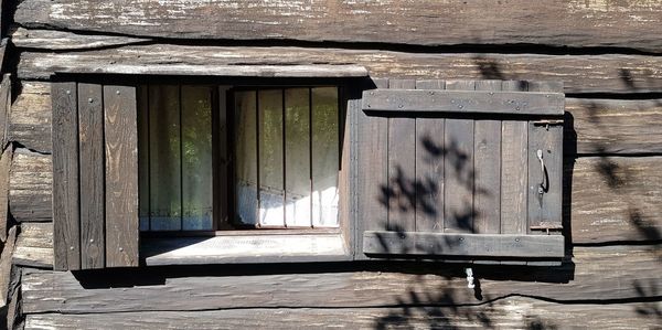 Close-up of open window on wooden door of building