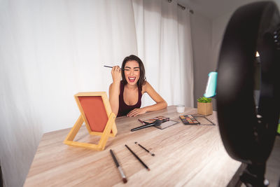 Young woman sitting on table at home